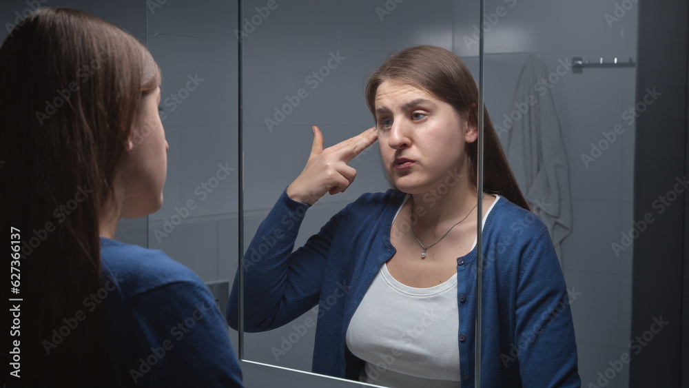 Upset stressed woman looking in her reflection in mirror and pretending to shoot herself in temple with fingers. Concept of depression, suicide, stress, mental illness, loneliness and frustration. Upset stressed woman looking in her reflection in mirror and pretending to shoot herself in temple with fingers. Concept of depression, suicide, stress, mental illness, loneliness and frustration.