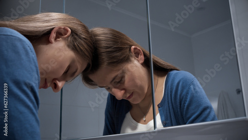 Tableau sur toile Portrait of angry and stressed woman leaning on mirror and looking in reflection
