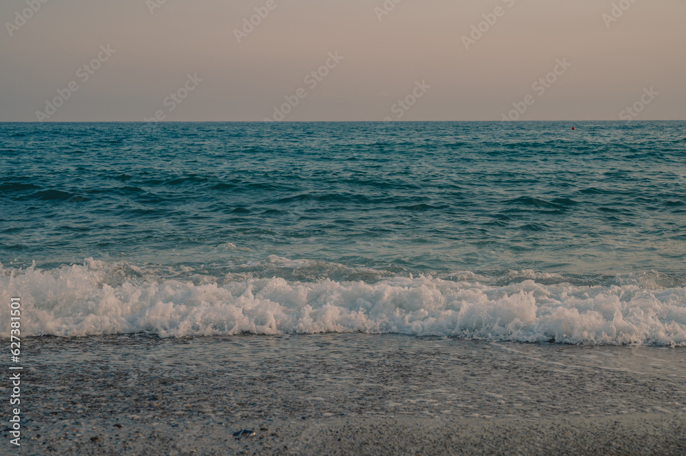 Waves of Mediterranean Sea rolling to the sandy Turkish beach. Beautiful Turkish evening.