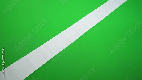 Roll of toilet paper unrolls on a green floor