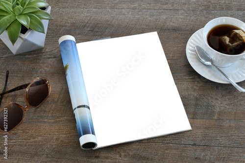 An open magazine laying on a table or desk with a white blank page for mock up.