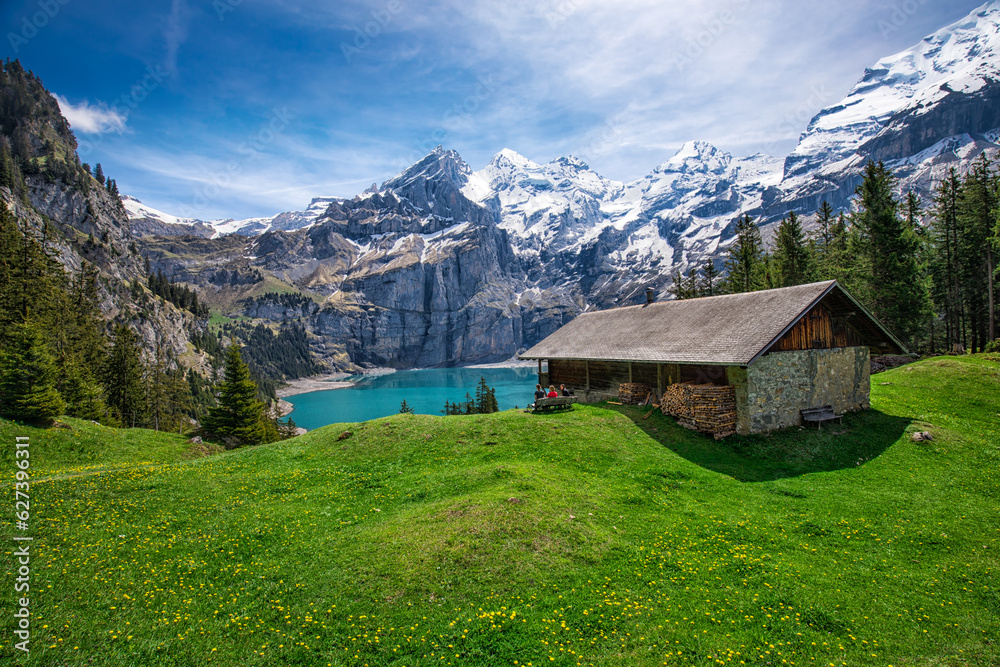 Obraz premium Amazing tourquise Oeschinnensee with waterfalls, wooden chalet and Swiss Alps, Berner Oberland, Switzerland.