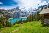 Amazing tourquise Oeschinnensee with waterfalls, wooden chalet and Swiss Alps, Berner Oberland, Switzerland.