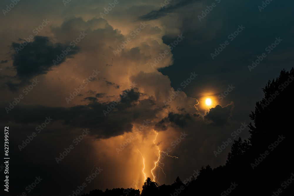 Lightning strike and moon with storm clouds at night