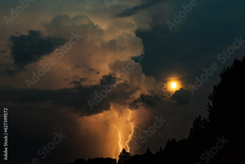 Lightning strike and moon with storm clouds at night