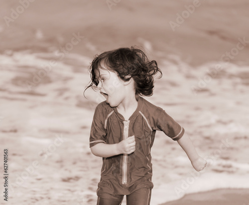 Sepia toned image of a young girl running from the surf on the shore of Kamaole Beach; Maui, Hawaii, United States of America photo