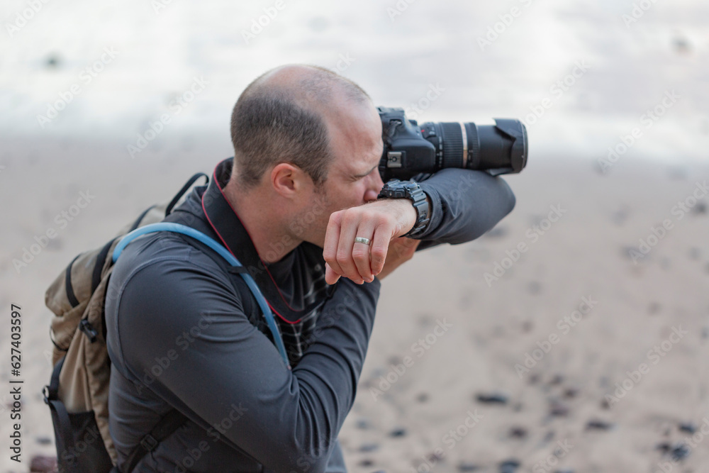 Close-up of a man using his arm to balance camera with telephoto lens, photographing the view on the Road to Hana; Maui, Hawaii, United States of America