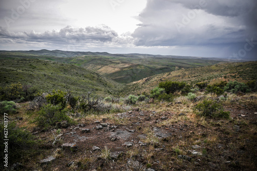 High desert terrain of rolling green mountain sides near Twin Falls Idaho in summer with stormy skies