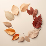Circle arrangement of autumn leaves on soft tan background.