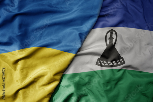 big waving national colorful flag of ukraine and national flag of lesotho .