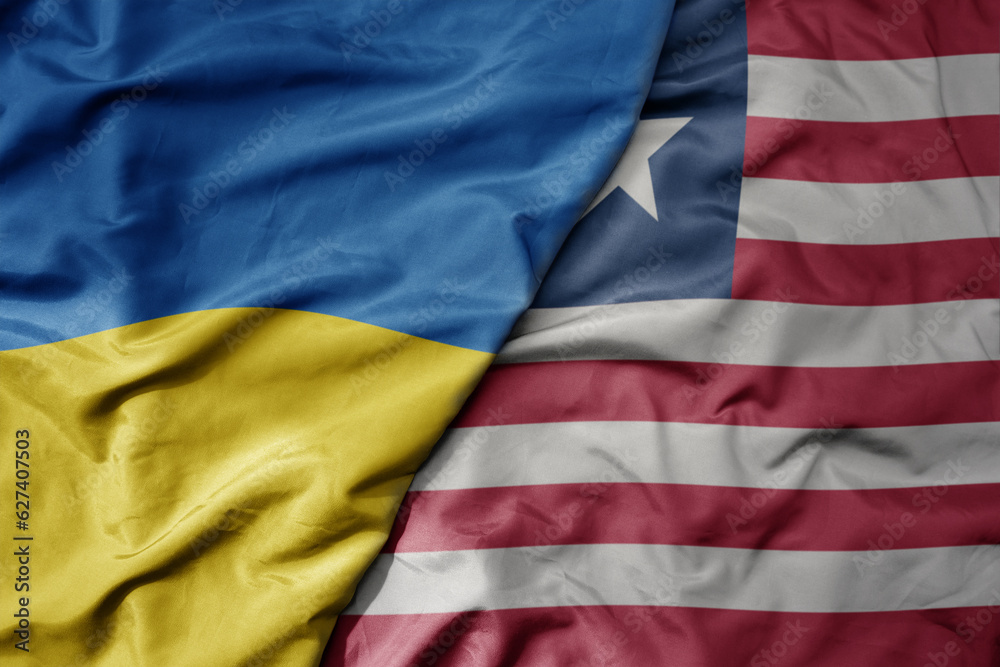 Obraz premium big waving national colorful flag of ukraine and national flag of liberia .