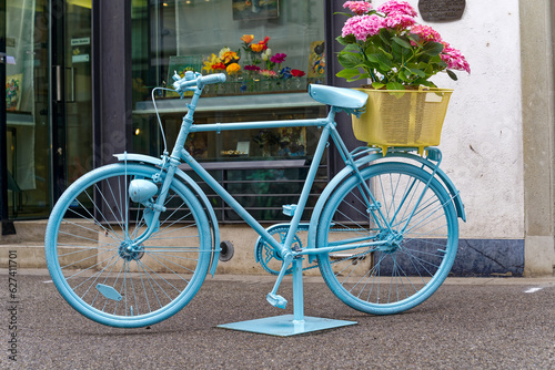 Blue painted bicycle with basked with pink hydrangea flowers at the old town of Swiss City of Winterthur on a cloudy spring day. Photo taken May 17th, 2023, Winterthur, Switzerland.