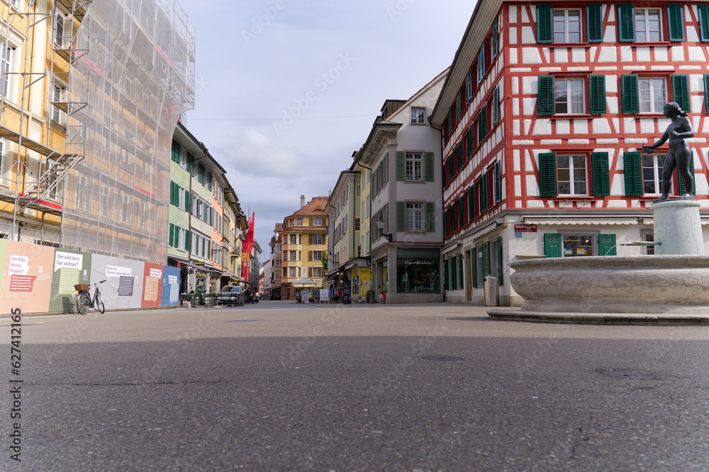 Alley at the medieval old town of City of Winterthur with colorful facades of historic houses and fountain on a cloudy spring day. Photo taken May 17th, 2023, Winterthur, Switzerland.