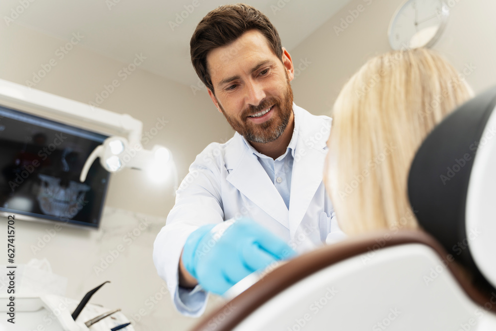 Handsome bearded dentist preparing female patient to checking teeth Handsome bearded dentist preparing female patient to checking teeth