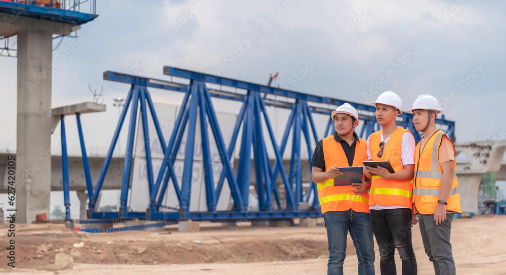 Group of asian engineers discuss about work at site of building under construction,The contractor team discusses the design of the structure,Three workers are working outside. Group of asian engineers discuss about work at site of building under construction,The contractor team discusses the design of the structure,Three workers are working outside.