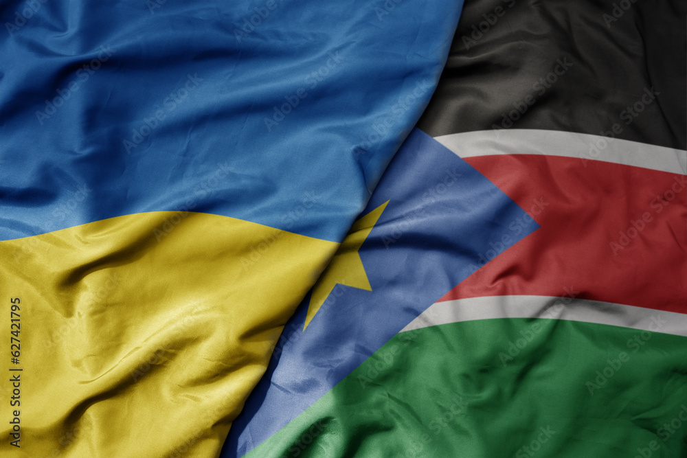big waving national colorful flag of ukraine and national flag of south sudan . big waving national colorful flag of ukraine and national flag of south sudan .