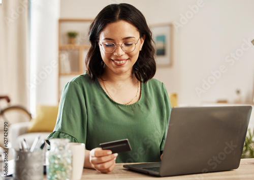 Online shopping, laptop and credit card, woman at table in living room for internet banking app in home with tech. Ecommerce payment, smile and cashback, girl at computer browsing retail website sale
