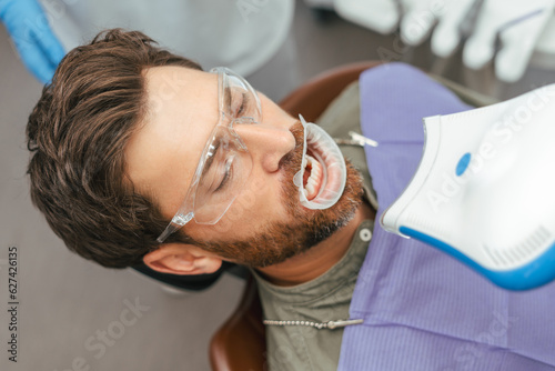 Fotografía Man having irradiating with ultraviolet light teeth during whitening procedure