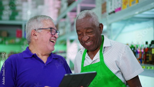 Senior Manager Presenting Tablet Screen to Senior African American Grocery Store Employee