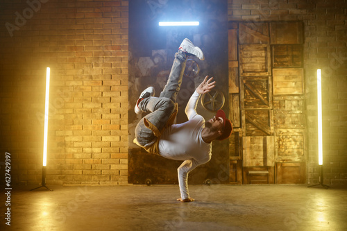 Young adult man breakdancing doing one handed handstand