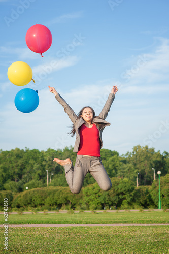 Young beautiful happy business woman with long hair jumping with air balloons outdoor