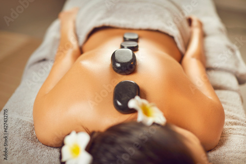 Unrecognizable young man lying on a spa bed, relaxing, getting beauty treatments, and enjoying an exotic back massage with hot stones. Spa treatment, body relaxation, skin care concept