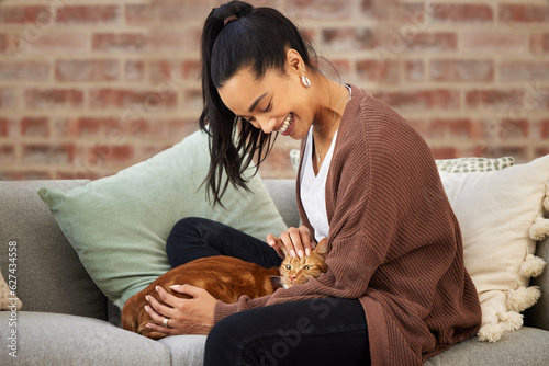 Love, woman with her cat and on a sofa in living room of her home sitting. Animal care or support, quality or bonding time and happy female person pet her kitten on a couch together at her house