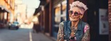 A woman aged 50+ with tattoos stands on the street and. looking to the side, portrait. Banner.