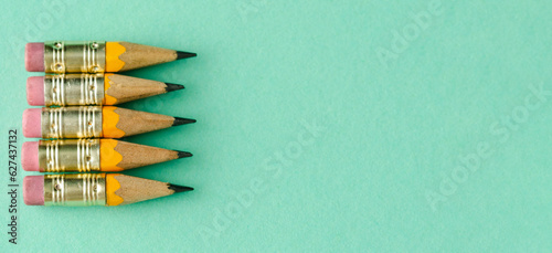 Five mini wooden pencils on a blue background. Back to class. Copy space. Top view. Extra long photo.