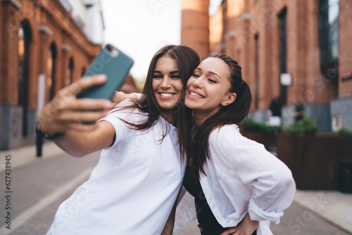 Cheerful friends taking selfie on street
