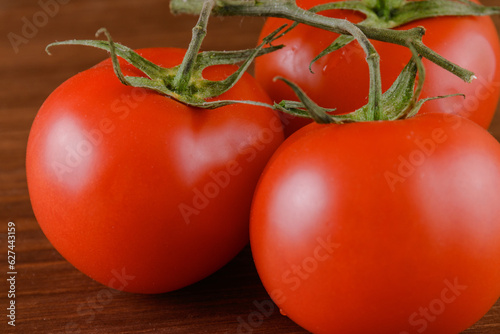 Fresh, ripe red tomatoes on wood background. Closeup of tomato branch.