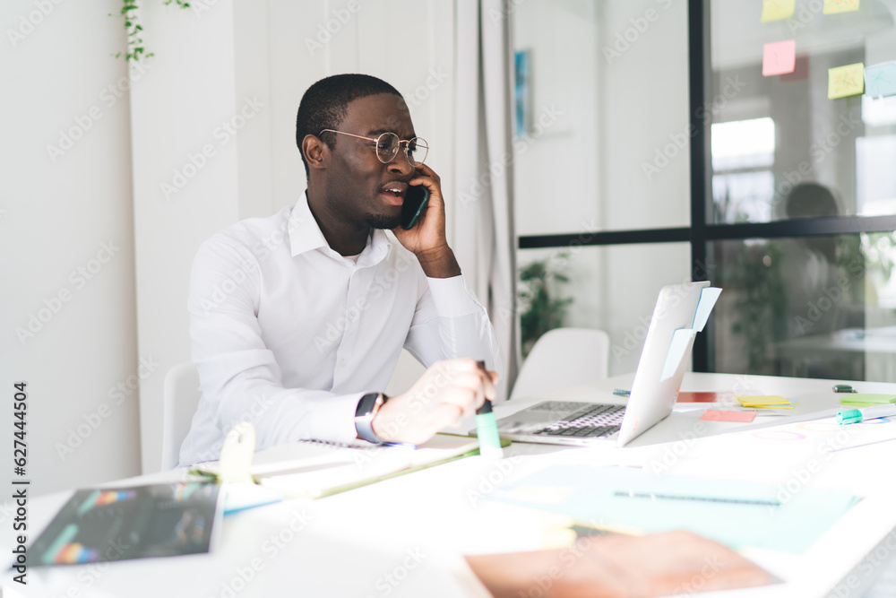 Focused ethnic businessman speaking on smartphone in office Focused ethnic businessman speaking on smartphone in office