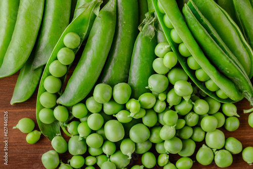 Green pea and pea pods. Pea on wooden table. Closeup of fresh pea. Pea pod with beans.
