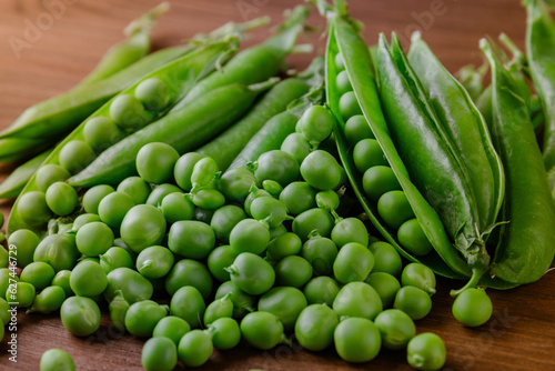 Green pea and pea pods. Pea on wooden table. Closeup of fresh pea. Pea pod with beans.