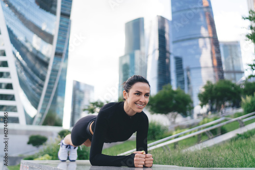 Content determined sportswoman doing plank exercise in park photo