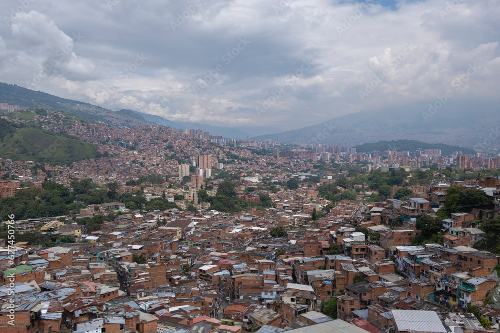 Aerial panoramic view of poor neighborhoods and favelas built of red brick in city's outskirt. Comuna 13, Medellin, Colombia.