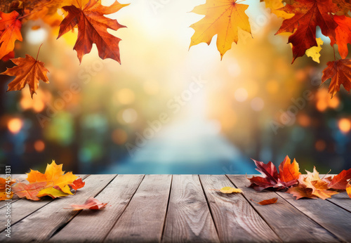 Empty wooden table with fall leaves  glowing sun and blurry seasonal colors. Autumn copy space background.