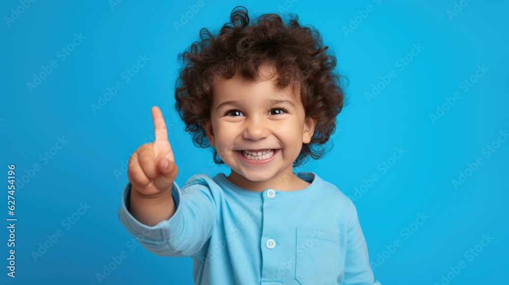 Child wearing casual clothes pointing with hand and finger to the side looking at the camera. Child wearing casual clothes pointing with hand and finger to the side looking at the camera.