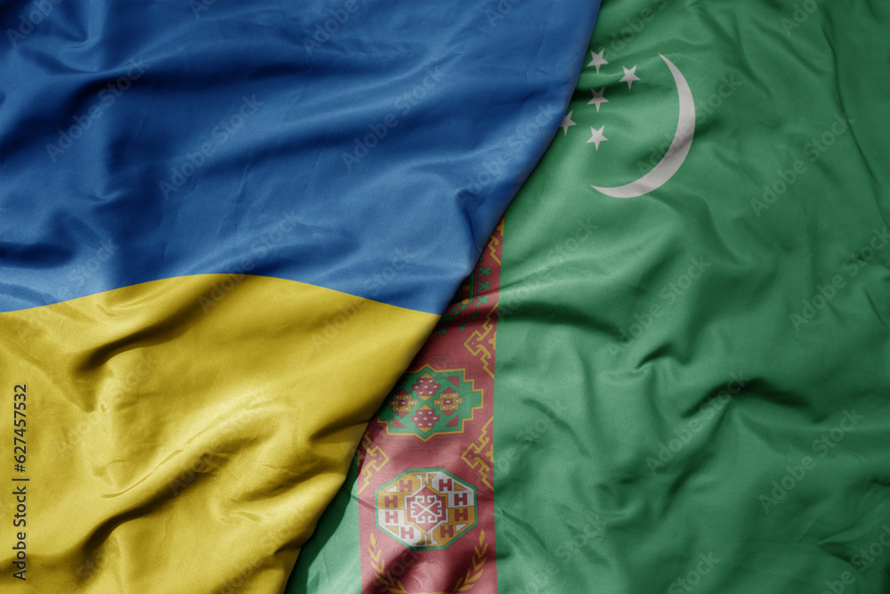big waving national colorful flag of ukraine and national flag of turkmenistan .