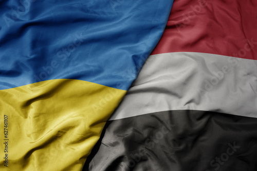 big waving national colorful flag of ukraine and national flag of yemen . photo