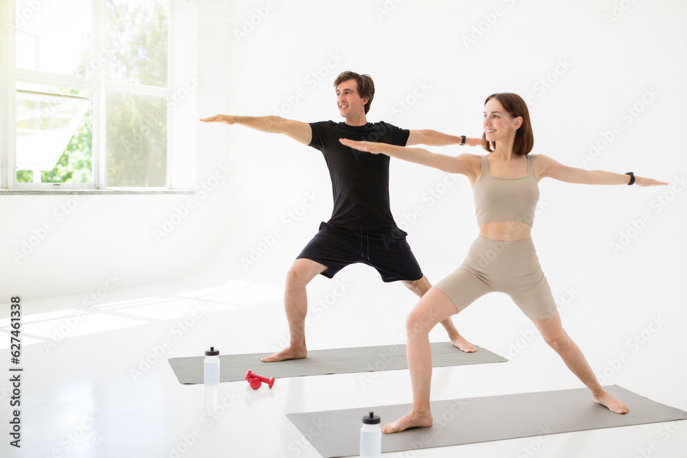 Naklejka premium Cheerful young caucasian lady and guy in sportswear enjoy workout together, practice yoga with water
