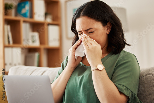 Remote work, laptop and sick woman on a sofa with flu, cold or viral infection in her house. Freelance, sneeze and lady online with allergies, virus or burnout, sinusitis or hayfever while working photo