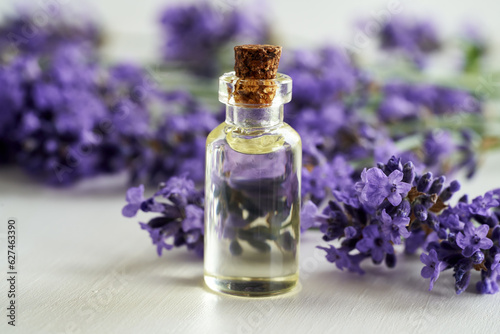 A transparent bottle of essential oil with fresh lavender flowers