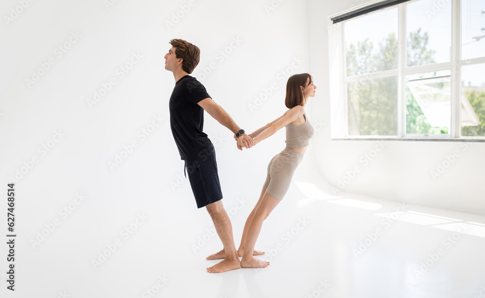 Fototapeta premium Happy calm young caucasian lady and guy in sportswear enjoy workout together, stretching body, meditate