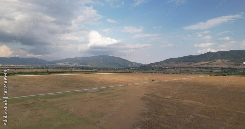 Clear yellow field with mountains drone shot Clear yellow field with mountains drone shot