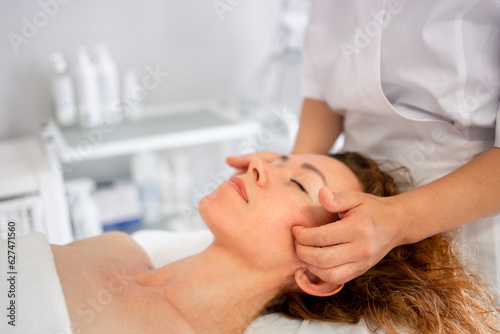 Massage therapist massaging woman face and body