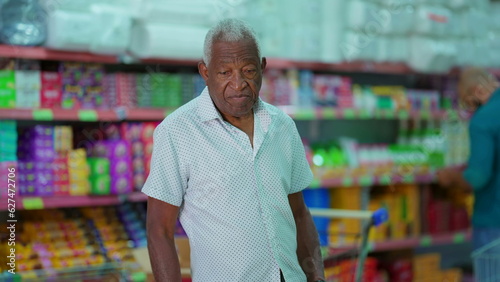 One black Brazilian senior customer looking for products at grocery store. African American man searching for food items, consumer lifestyle