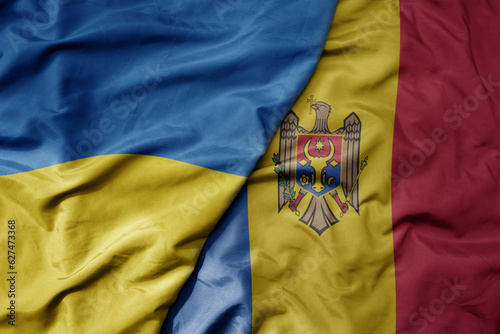 big waving national colorful flag of ukraine and national flag of moldova . photo