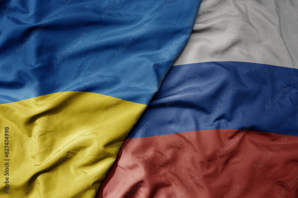 big waving national colorful flag of ukraine and national flag of russia .