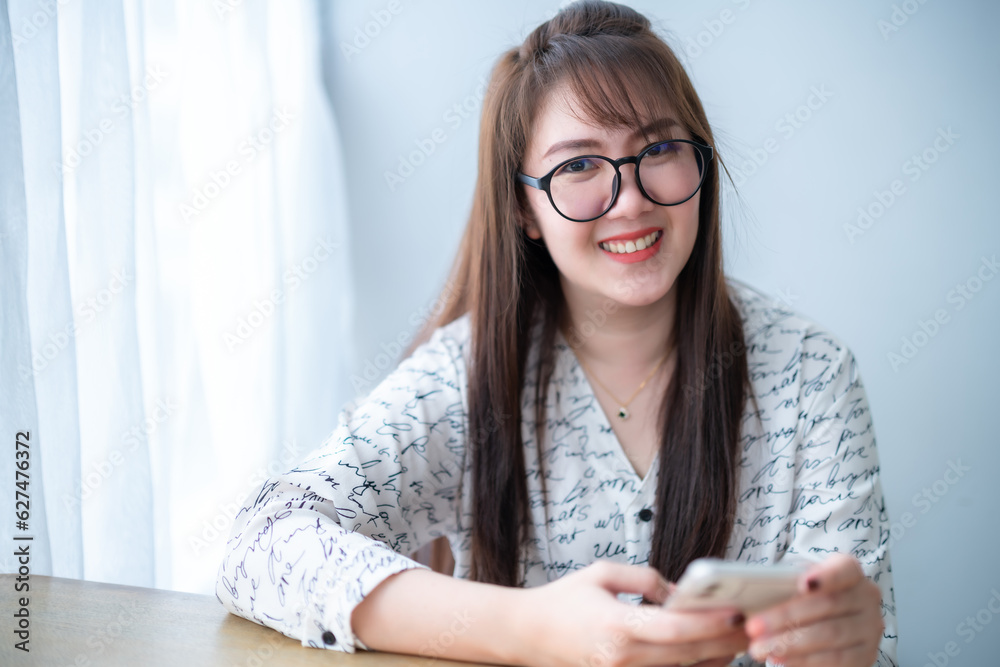 Portrait of beautiful happy Smiling asian woman relaxing writing message on smartphone sitting on sofa on comfortable couch at home in living room